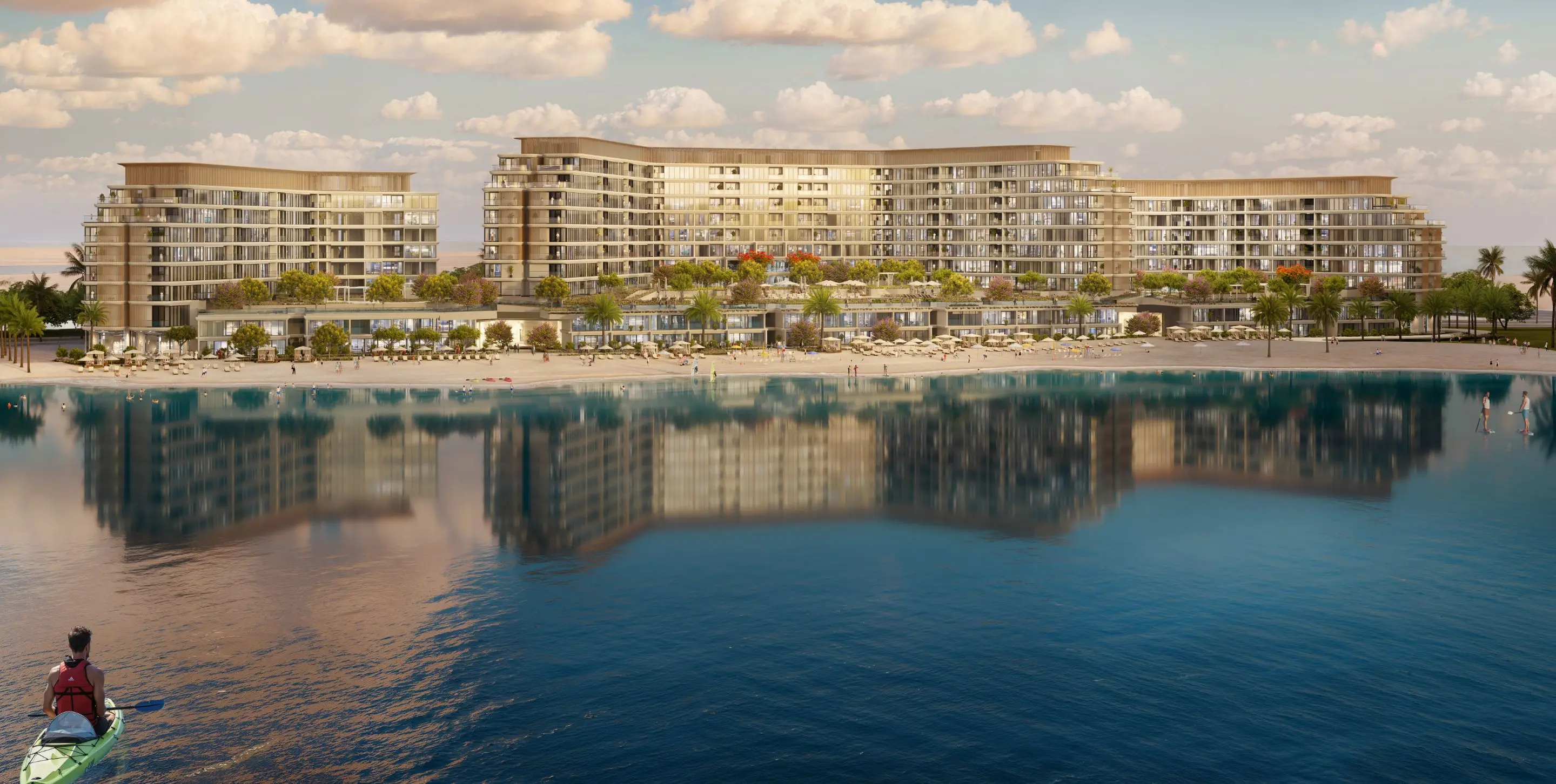 Render of Aquamarine's mid-rise blocks behind a palm-lined beach at sunset, reflected in the lagoon, with a kayaker in the foreground