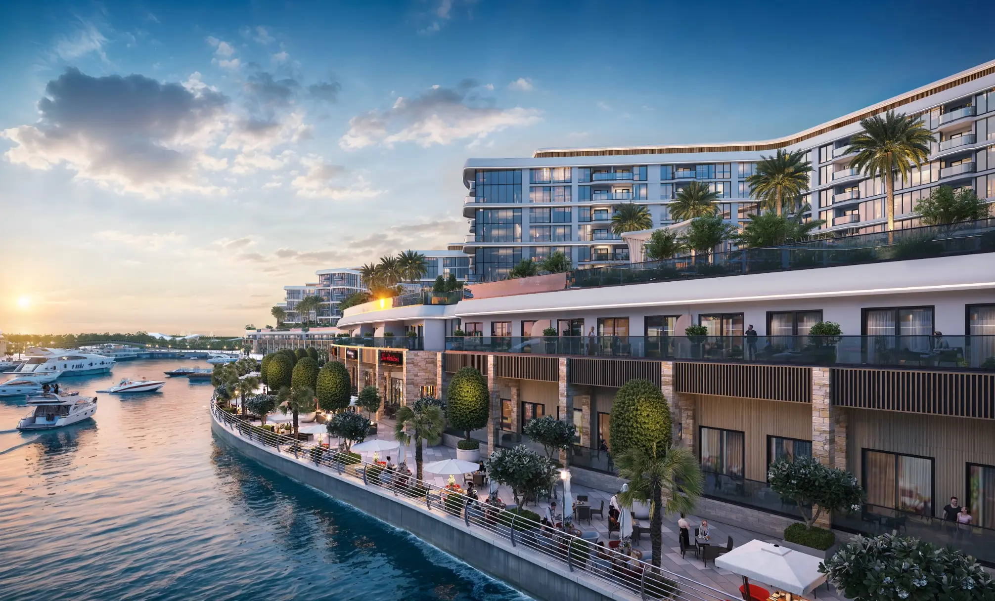 Render at sunset of an apartment block above a quayside promenade of cafés, with boats on the water and a bridge in the distance