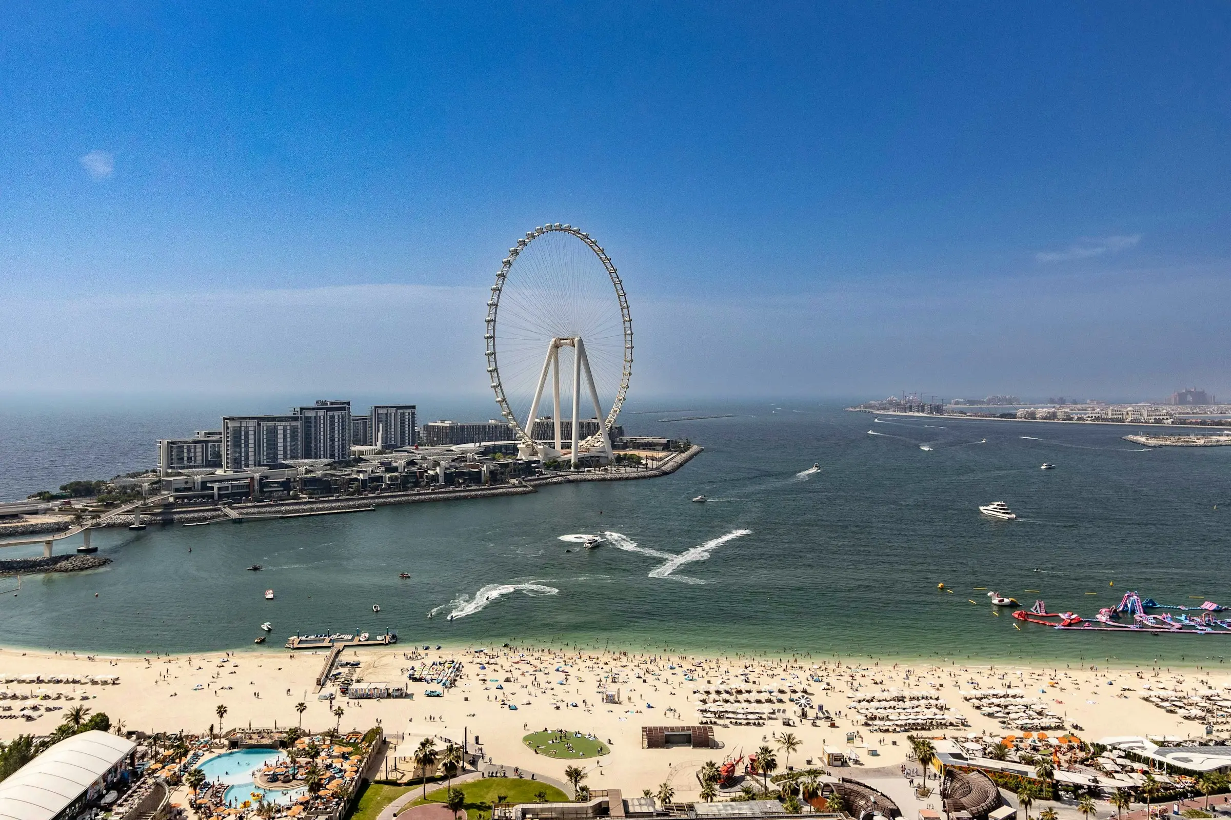Bluewaters and Ain Dubai seen from above JBR beach, with jet skis on the water and the footbridge on the left