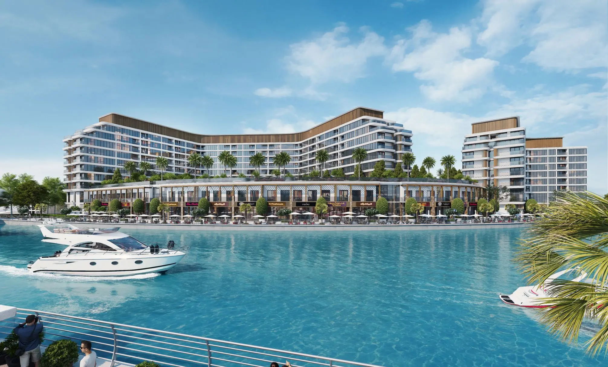 Render of a long V-shaped apartment block and a separate taller block above canal-front shops, with a motor cruiser on the water