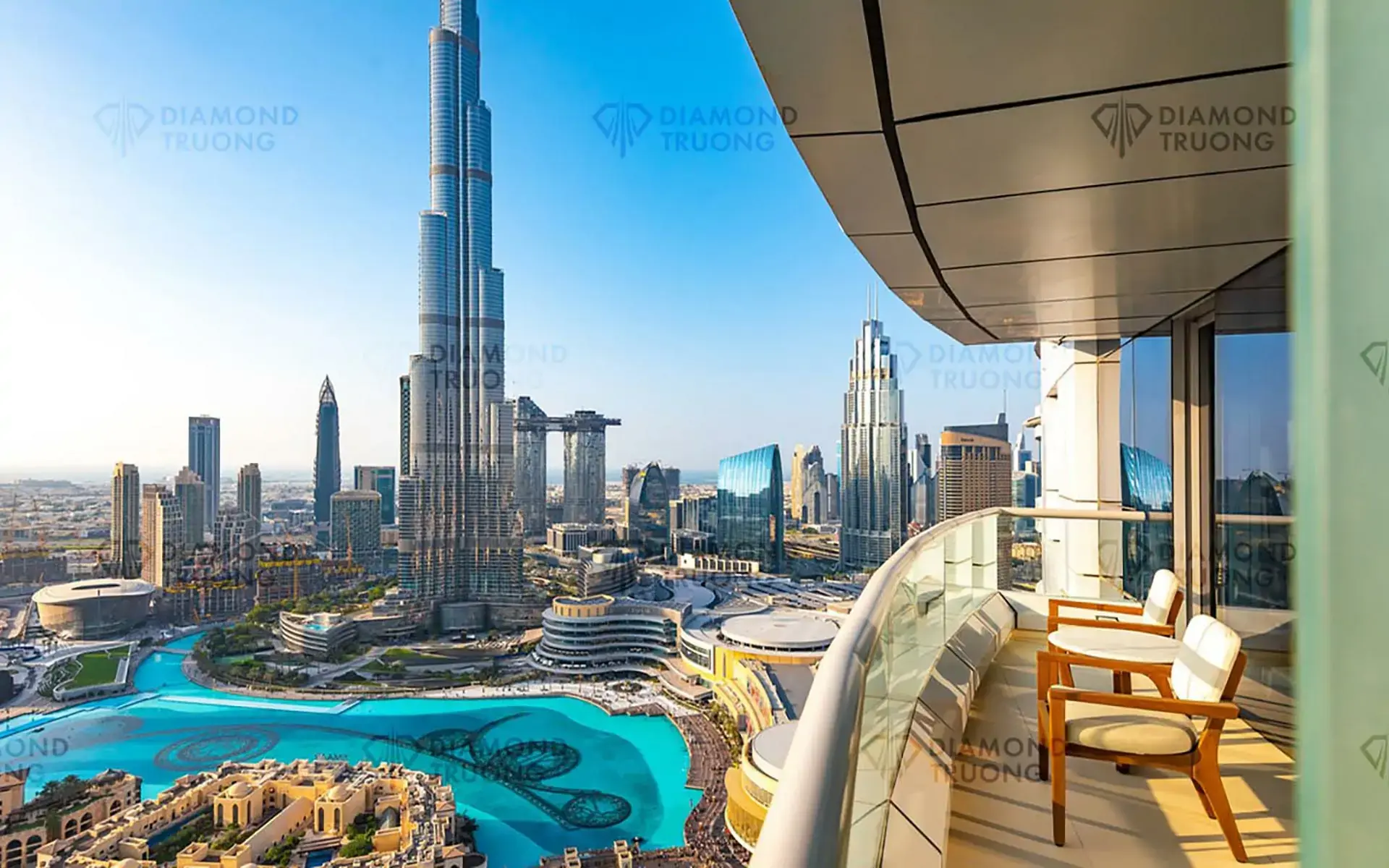 A curved balcony with two chairs, looking over Burj Lake to the Burj Khalifa