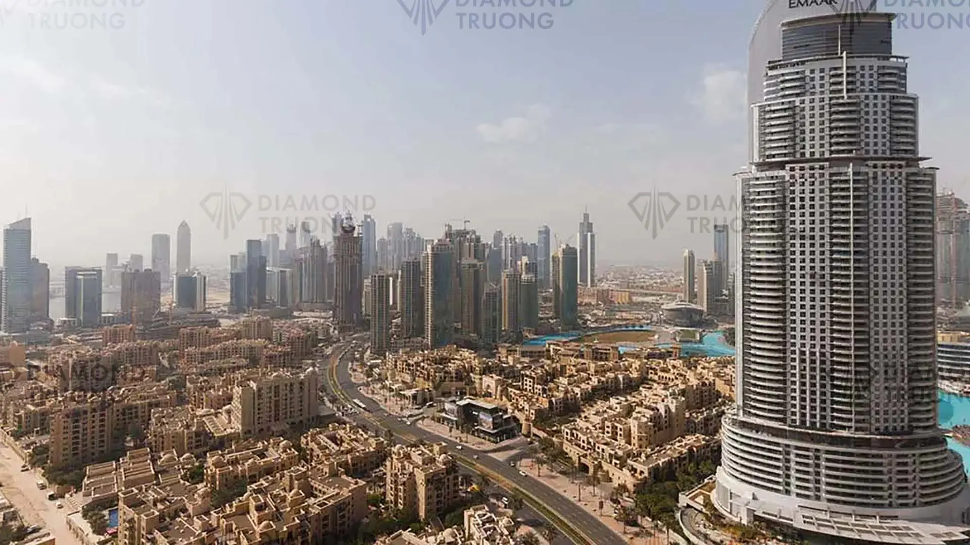 Downtown Dubai by day: a tall hotel tower on the right, low-rise sand-coloured apartment blocks and the lake, towers beyond