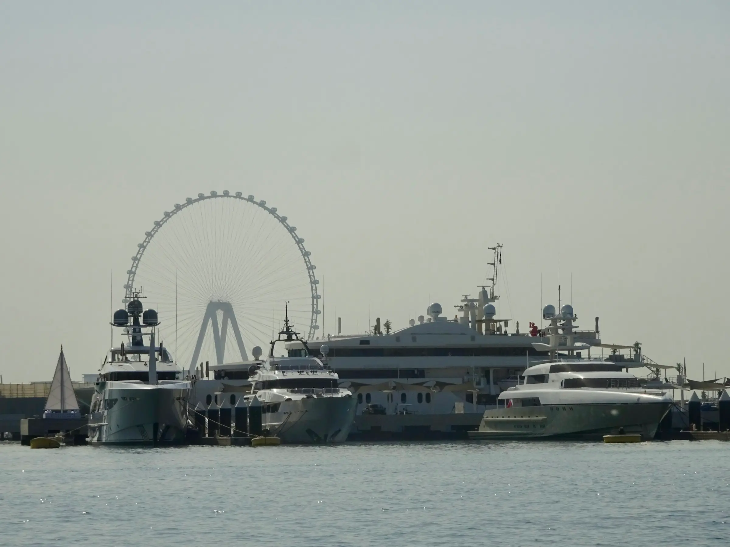 Superyachts moored in the marina, with Ain Dubai behind