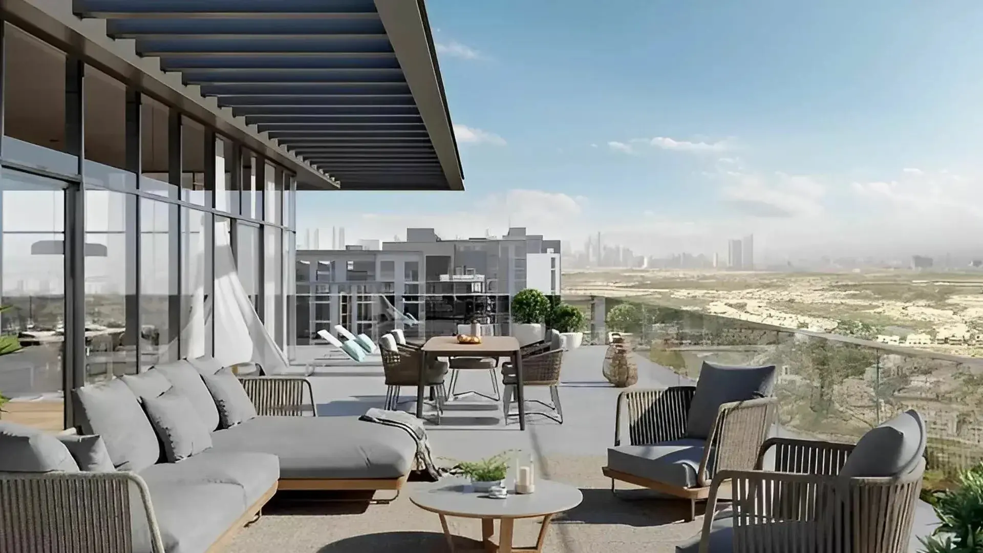 Render of a penthouse terrace with outdoor sofas and a dining table, looking over low-rise buildings and open land to a hazy skyline
