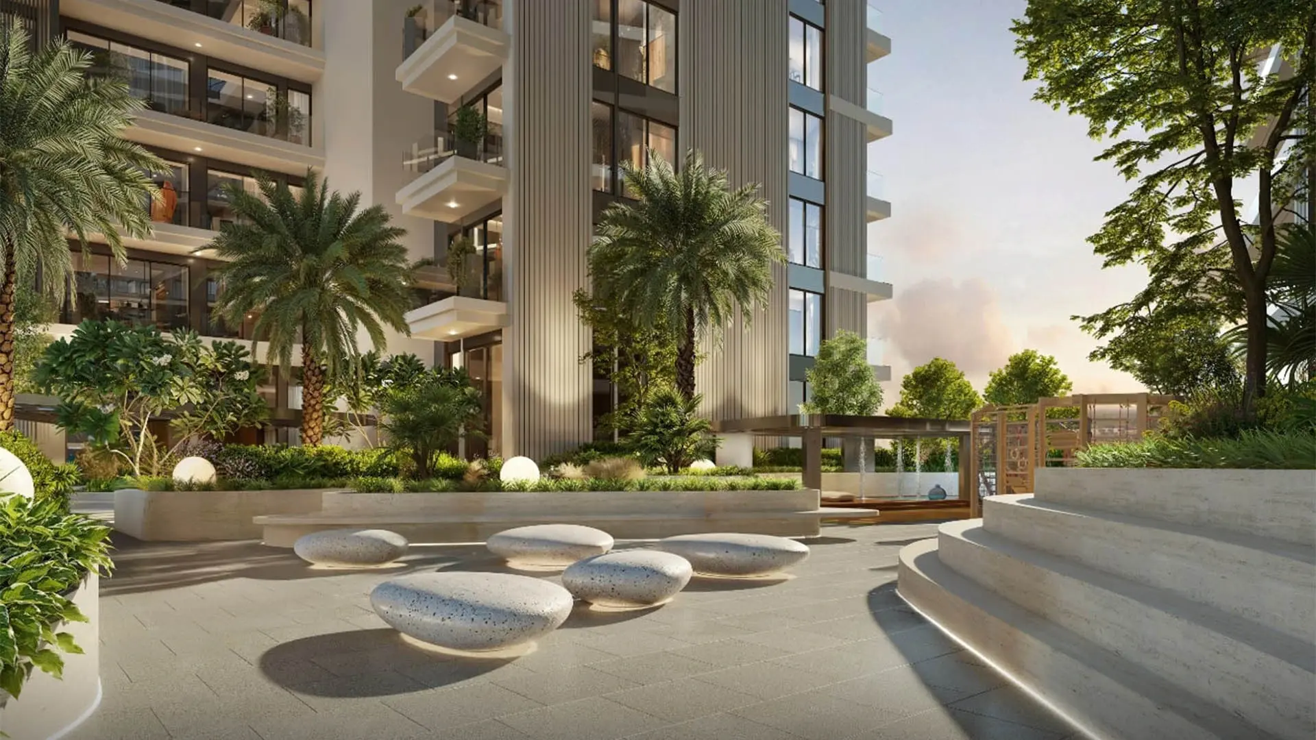 Ellington's render of The Hillgate's garden in Dubai Silicon Oasis: stone seats and steps below an apartment tower, with palms