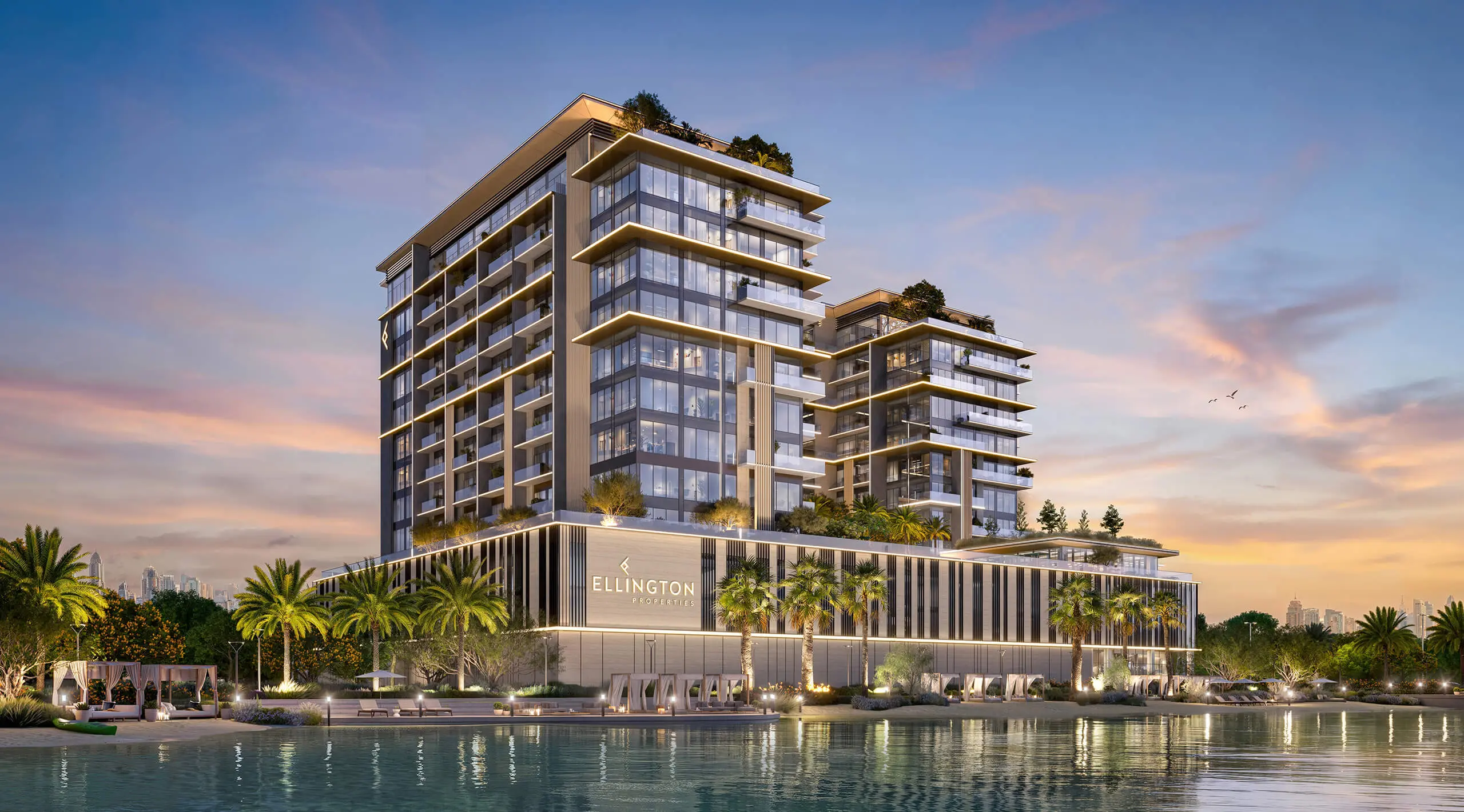 Render of Everly Place across the crystal lagoon at dusk, two stepped wings rising above a palm-lined podium