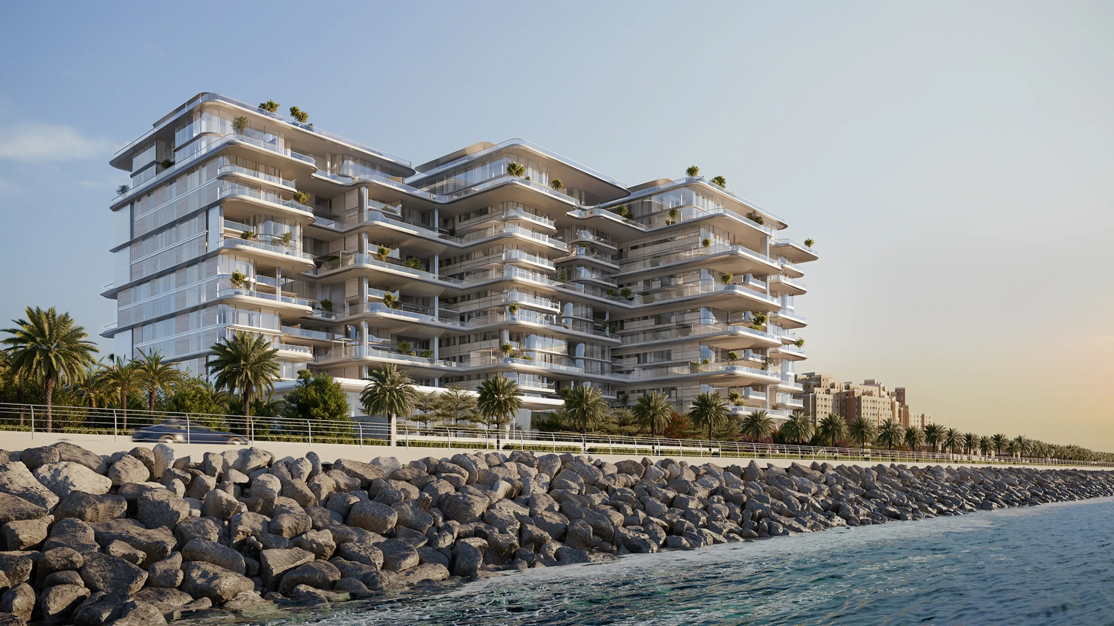 Render of Orla's stepped, linked towers above a rock-lined shore and a palm-lined promenade at sunset