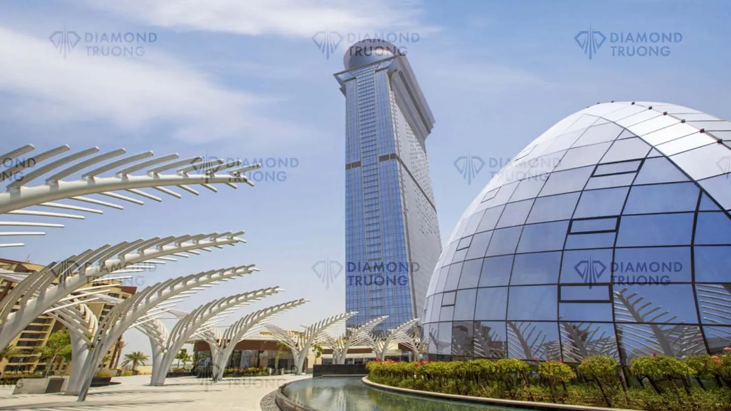 The Palm Tower on Palm Jumeirah's trunk, beside a glass dome and white palm-frond sculptures over a pool