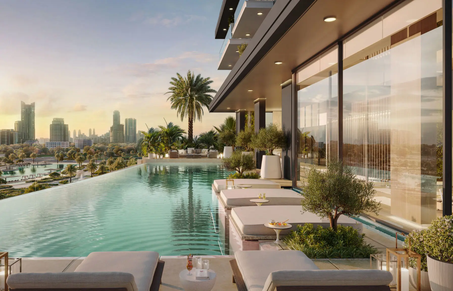 Render of an infinity pool on a terrace at sunset, with in-water loungers, an olive tree and towers on the skyline