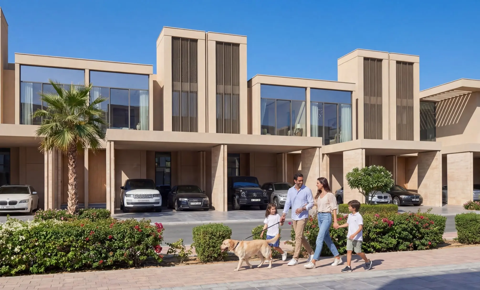 Row of joined sand-coloured villas with covered parking and a family walking a dog, from Sobha's marketing images for Sobha Sanctuary